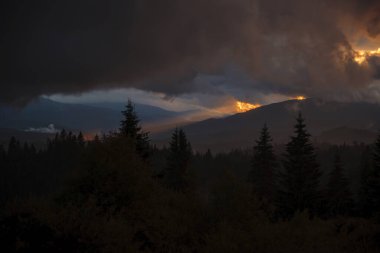Dramatic Sunset Over Forested Mountains