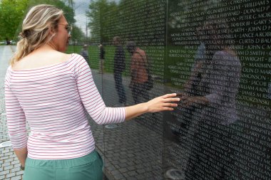 Genç bir kadın Washington 'daki Vietnam Anıtı' na dokunuyor.