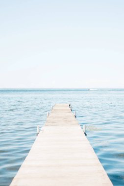 Wooden dock extending into calm blue water under a clear sky.