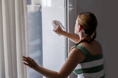 Evde pencereyi temizleyen kadın