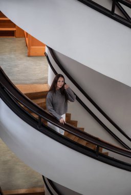 Modern binada sarmal merdivenlerde poz veren zarif bir kadın.