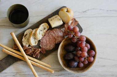 Charcuterie board with cheese, grapes, pear, nuts, and wine on a table