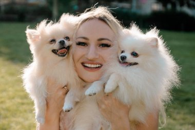 İki Pomeranya köpeğiyle gülümseyen kadın.