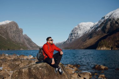 Kayalıklarda oturan ve dağların manzarasının tadını çıkaran adam.