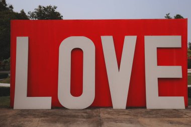 Açık hava parkında parlak kırmızı arka planla süslenmiş büyük bir aşk işareti.