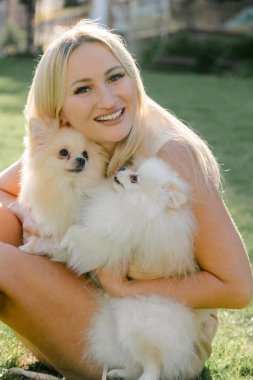 İki tüylü Pomeranya köpeğine sarılan kadın