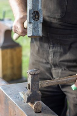Demirci örs üzerinde çekiç ve keski hazırlıyor.