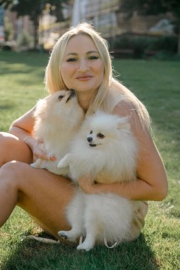 İki pomeranya köpeğine sarılan bir kadın.