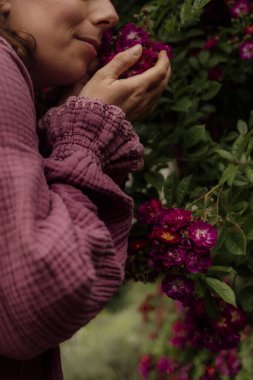 Bahçedeki güllerin kokusunu alan bir kadın..