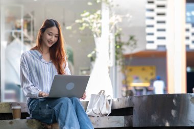 Önünde dizüstü bilgisayarı olan bir kadın merdivende oturuyor.