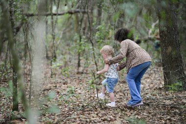 Büyük çocuk, yürümekte olan bebeğe orman yolunda rehberlik ediyor..