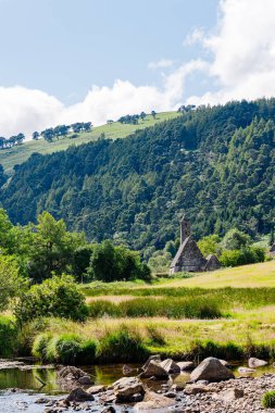 Stone church ruins in Glendalough valley with forested hills