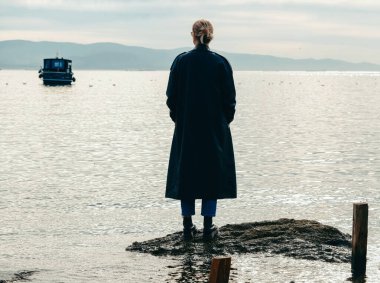 Manzaralı deniz manzaralı kayalık sahilde yalnız bir kadın.