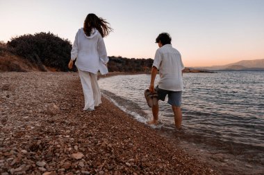 Çift gün batımında sahilde yürüyor.