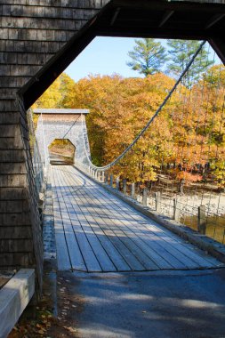 Scenic wire bridge over a river in Maine surrounded by fall foliage