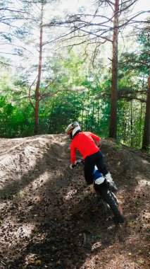 Dayanıklı bir adam arka taraftan, ormanda bir arazi bisikletinden atlar.