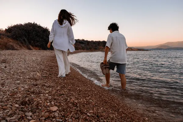 Çift gün batımında sahilde yürüyor.