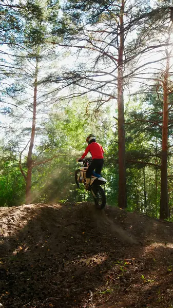 Dayanıklı bir adam arka taraftan, ormanda bir arazi bisikletinden atlar.