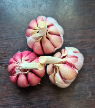 evocative close-up image of three bunches of garlic on dark wooden background