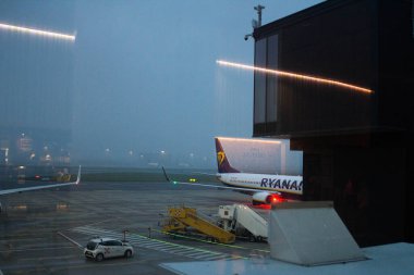 2021.10.31 Bergamo, Orio Al Serio Havaalanı, arka planda Ryanair uçaklarının bulunduğu bir havaalanı penceresinde neon ışıklarının yansımasının canlandırıcı görüntüsü. 