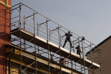 evocative image of workers engaged in assembling a scaffolding for a buildingto be restructured