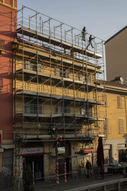 evocative image of workers engaged in assembling a scaffolding for a buildingto be restructured