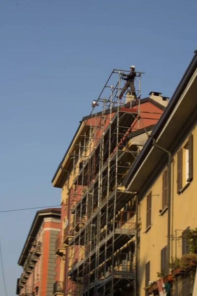 evocative image of workers engaged in assembling a scaffolding for a buildingto be restructured