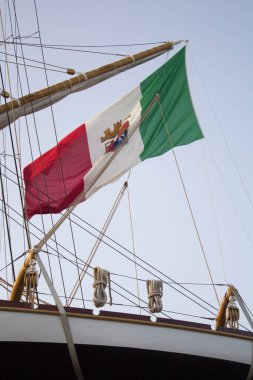evocative image of an Italian flag hanging from the stern of a sailing vessel
