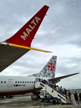 2022.06.28 Milan Malpensa Havaalanı, Malta Havaalanı. Ulusal havaalanı bayrağı, uçağın kuyruğunda yolcu alımının anımsatıcı görüntüsü.