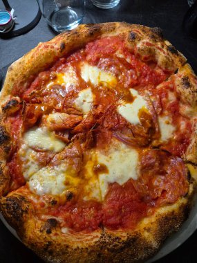 Domatesli, mozarellalı, baharatlı salamlı ve biberli bir pizzanın canlandırıcı görüntüsü.