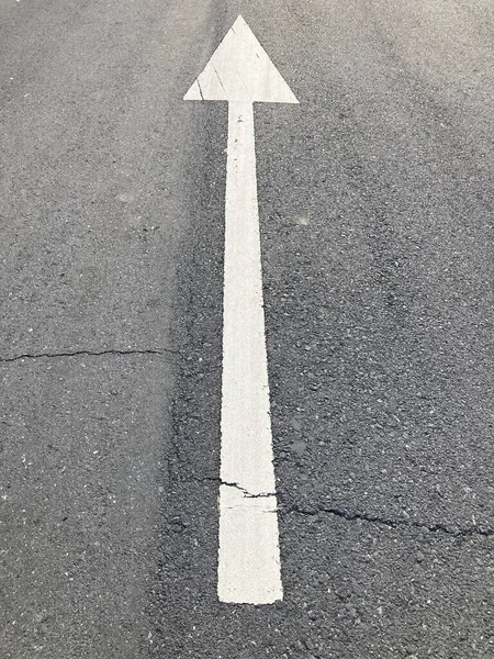 灰色沥青路面上的白色箭头标志 裂缝很大 在自然光下被毁 — 图库照片