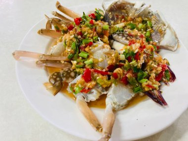 Taze biberli taze at yengeç salatası, sarımsak ve beyaz bir masaya konmuş baharatlı deniz ürünleri sosu.