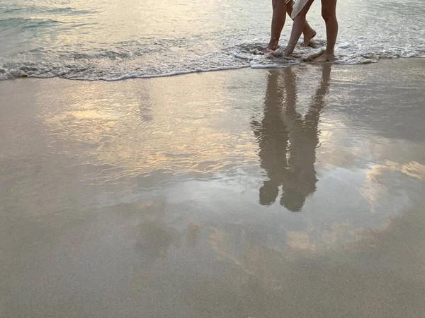 一对在夕阳的海滩上散步的情侣的腿 在清澈的沙滩上闪烁着香草般的天空 — 图库照片