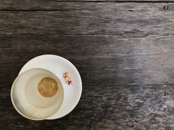 天然のダークブラウンの木のテーブルの上に白いソーサーの上に装飾されたかなり小さな花とホットカプチーノコーヒーのカップを終えた — ストック写真