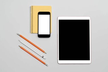 Tablet ve telefon, izole ekran, not defteri, masada duran kalemler. Beyaz izole ekranlı minimalizm modeli. Eğitim konsepti. Çevrimiçi Çalışma ve Uzaklık Öğrenme.
