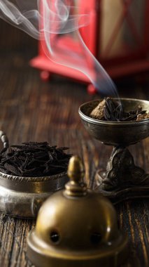 Burning incense with smoke in a rustic setting, the smoke of burning incense filling the air in a natural, rustic setting such as a cabin or a wooden room. The rustic setting adds a sense of serenity