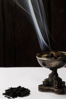 Burning incense on a white background, the image captures the smoke of burning incense in a high contrast black and white setting