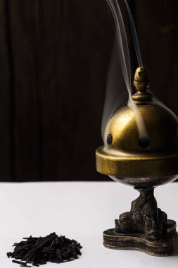 Burning incense with smoke in a rustic setting, the smoke of burning incense filling the air in a natural, rustic setting such as a cabin or a wooden room. The rustic setting adds a sense of serenity