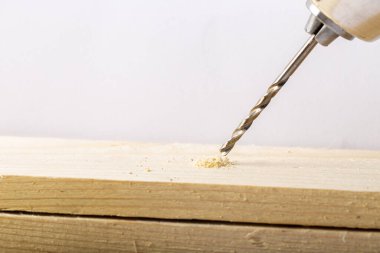 Bir matkabın yakın çekimi tahtada bir delik açıyor.