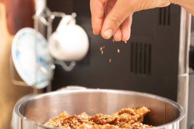 Delicious chebakia pastries. Crafted puff pastry, honey and sesame seeds, Sprinkling sesame seeds on Chebakia, final stage of preparation.
