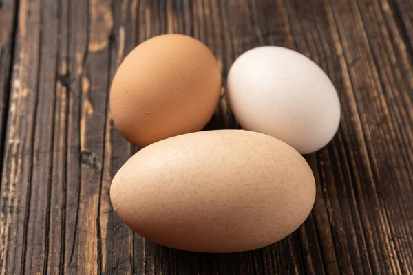 stock image A chicken egg with a double yolk stands out on a table background next to two smaller eggs.