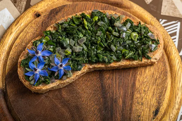 Stock image A crispy bread slice whole grain serves as a sturdy base for the ingredients atop, generously adorned with finely chopped borage leaves and diced onion for a flavorful punch and crunchy texture