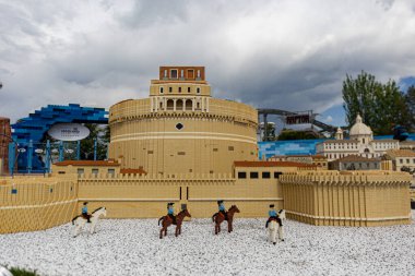 Gardaland, Verona, İtalya - 20 Nisan 2024: Mimari ayrıntılara, minyatür figürlere ve arka planda kısmen bulutlu gökyüzüne sahip tarihi binaların LEGO tuğlası kopyası.