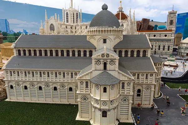 stock image Gardaland, Verona, Italy, April 20, 2024: Model of white cathedral with architectural details, green doors, miniature figures on decorated floor, under a blue sky.