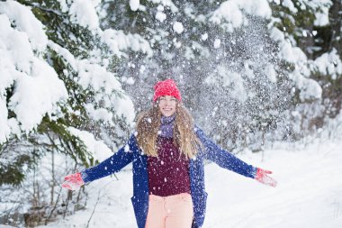 Parlak elbiseli gülen genç kadın parka kar atıyor, kış eğlencesi, kış zamanı.