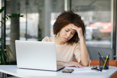 Yorgun Afrikalı Amerikalı genç kadın girişimci ya da ofis çalışanı bilgisayar işinden yorgun düşmüş