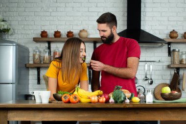 Çekici çift mutfakta organik sağlıklı yiyecekler pişiriyor. Mutfakta yemek pişiren ve sağlıklı salata yaparken birlikte eğlenen heyecanlı genç çift..