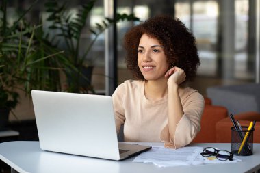 Bilgisayarında daktilo eden kendinden emin bir Afro-Amerikalı kadın modern bir ofiste doğal ışıkla dolup taşıyor. Başarı kavramı.