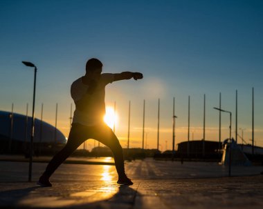 Gün batımında boks antrenmanı yapan bir adam.