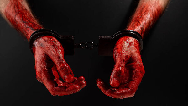 Крупный план окровавленных мужских наручников на черном фоне